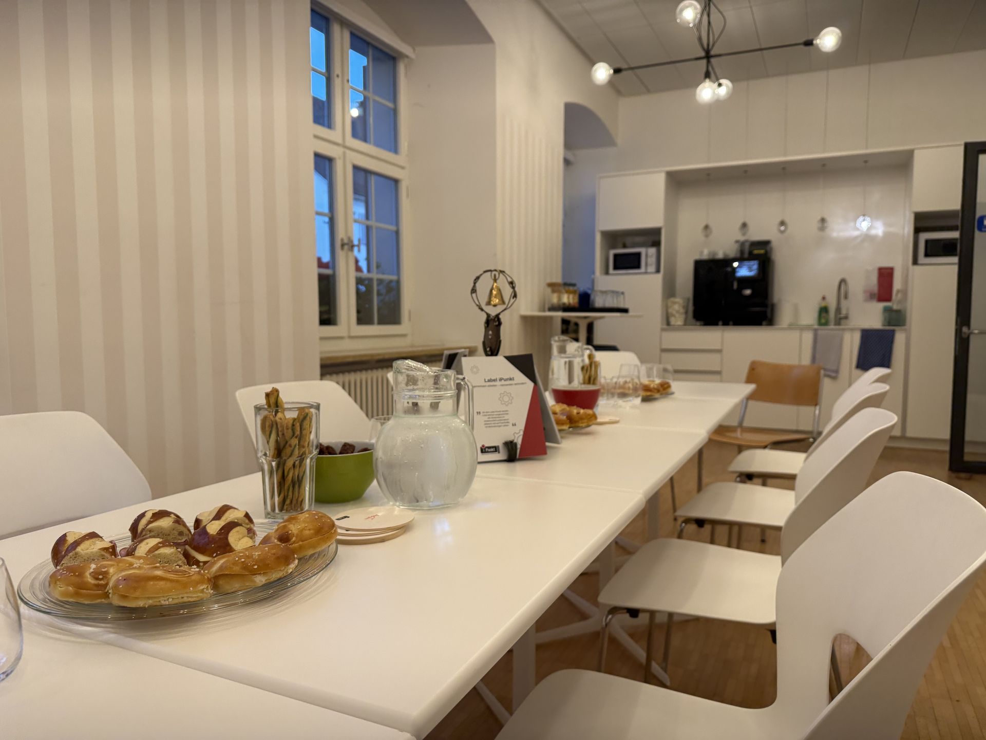 Für den iPunkt-Stammtisch vorbereiteter Sitzungsraum der Gemeindeverwaltung Arlesheim mit einem langen Tisch, weissen Stühlen, Getränken und Gebäck.